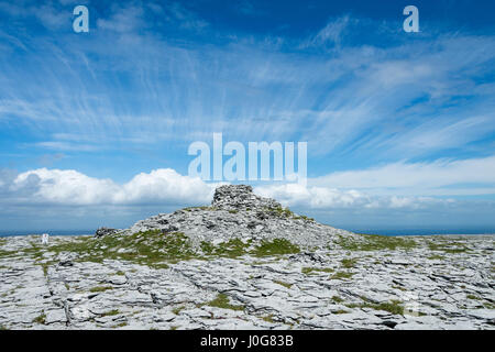 Pavimentazione di pietra calcarea e il Tumulo al vertice di Dobhach Bhrainin, Gleninagh montagna, Burren, County Clare, Irlanda Foto Stock