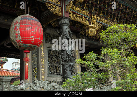 Grande lanterna rossa, un albero e una facciata ornata di Mengjia tempio Longshan in Taipei, Taiwan. Foto Stock