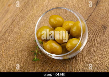 Olive farcite in heap la ciotola su uno sfondo di legno Foto Stock