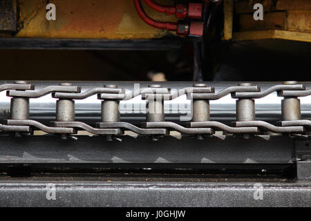 Il dispositivo di un caricatore di colore giallo sulla ferrovia. Grigio acciaio maglie di catena di guida del carrello meccanismo. Foto Stock