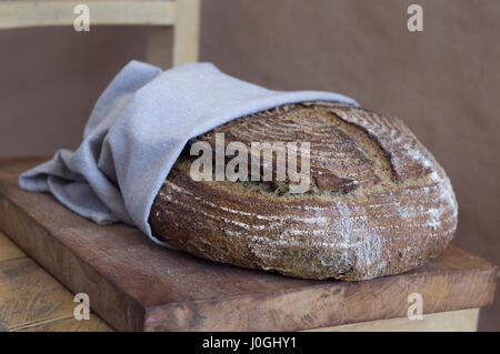 Bellissimo il pane artigianale in un asciugamano su una tavola di legno Foto Stock