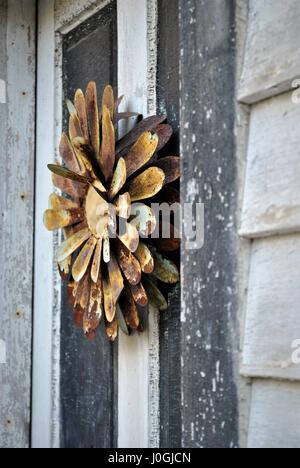 Arrugginito ghirlanda di fiori sulla porta vecchia Foto Stock