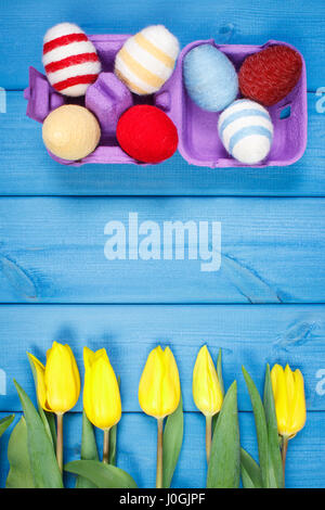 Bouquet fresco di tulipani gialli e uova di Pasqua avvolto stringa di lana blu su tavole di legno, copiare lo spazio per testo o iscrizione Foto Stock