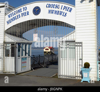 Mumbles Pier è una famosa icona marittima - ingresso con vista della scialuppa di salvataggio originale stazione attraverso di esso, Mumbles, Swansea, Regno Unito Foto Stock