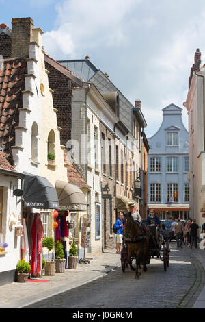 I turisti tenendo tradizionale cavallo e carrozza sightseeing ride in strada per lo shopping a Bruges, Belgio Foto Stock