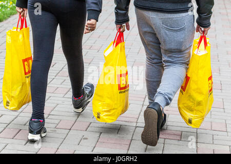 Clienti con merci acquistate da un supermercato borse merci riempite in sacchetti di plastica, vista posteriore posteriore Foto Stock