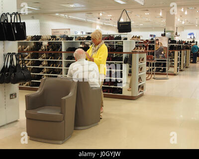 Interno del ramo di Manchester del department store di Marks & Spencer shop negozi nel centro città centro che mostra due persone mature guardando le scarpe. Foto Stock