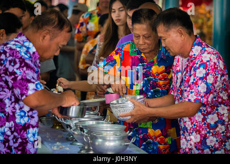 I membri della congregazione riempire ciotole di riso che sarà presentato ai monaci di un tempio sul primo giorno del Songkran nelle zone rurali a Nakhon Nayok, Thailandia, 13 aprile 2017. Foto Stock