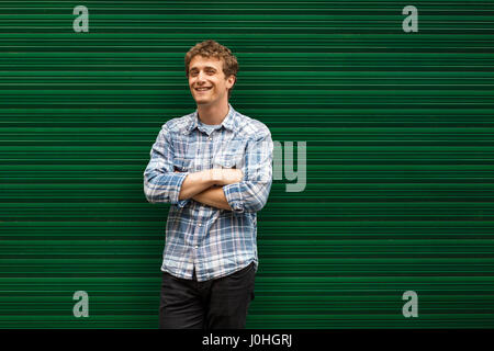 Sorridente giovane uomo vestiti casual in piedi contro lo sfondo di colore verde Foto Stock