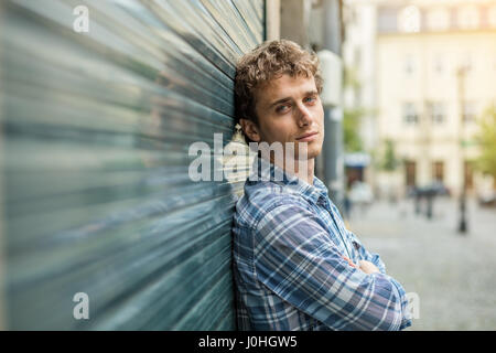 Giovane biondo e culry Uomo in camicia a scacchi standin esterno vicino a una parete Foto Stock