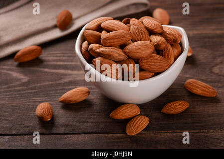 Mandorle in vaso in ceramica su legno scuro dello sfondo Foto Stock