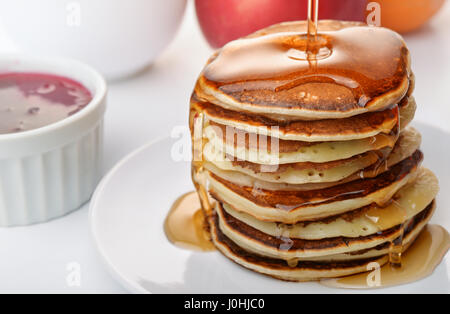 Stii vita con stack frittelle versando lo sciroppo marple Foto Stock