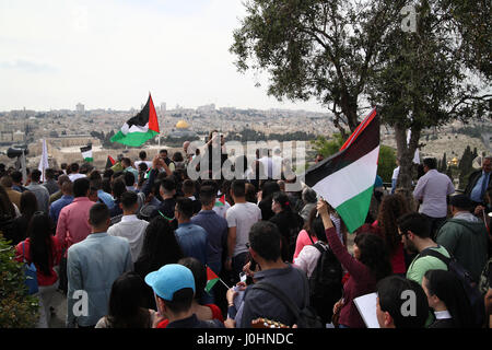 Palestinesi cristiani frequentano una domenica delle Palme processione sul Monte Olive azienda bandiere palestinese vedendo la Cupola della roccia sul Monte del Tempio in anticipo Foto Stock