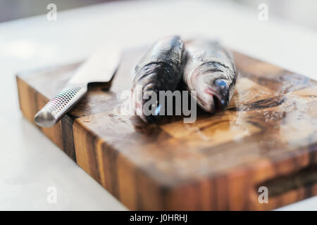 Branzino fresco su un tagliere Foto Stock