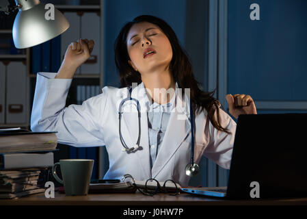 Giovani preoccupati medico avente male la diagnosi e il tratto di notte. splendida razza mista asian donna cinese modello. medico e di concetto di salute Foto Stock