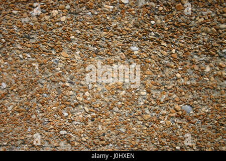 La superficie di una parete pebbledash che è piccole pietre brillare su di un mattone o superficie di cemento. Foto Stock