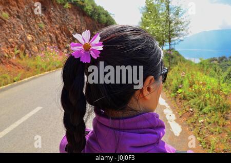 Ragazza con fiore viola in capelli camminando sulla strada e godersi l'estate Foto Stock