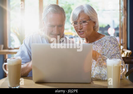 Coppia senior utilizzando computer portatile mentre un caffè in cafÃƒÂ© Foto Stock