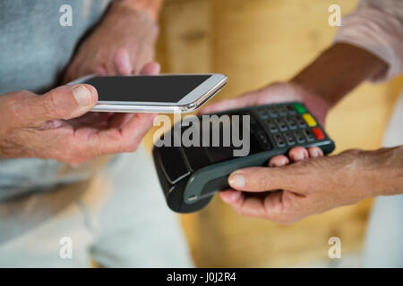 Il cliente effettuando il pagamento attraverso la tecnologia NFC sul telefono cellulare in cafÃƒÂ© Foto Stock