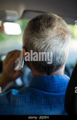 Vista posteriore del senior uomo parlando al telefono mentre si guida auto Foto Stock