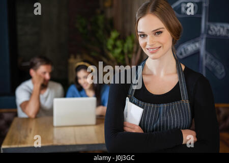 Ritratto del proprietario sorridente in piedi contro il cliente presso il cafe shop Foto Stock