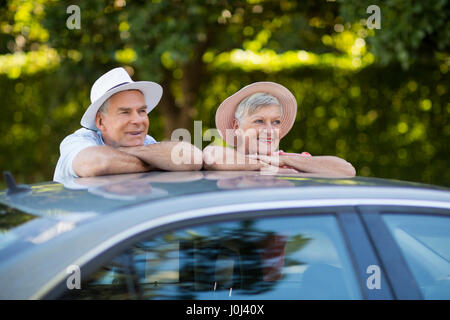 Felice coppia senior appoggiata sul tetto del veicolo Foto Stock