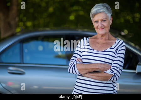 Ritratto di fiducia senior woman standing in auto Foto Stock