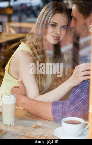 Close up di sorridere giovane seduto in cafe visto attraverso il vetro della finestra Foto Stock