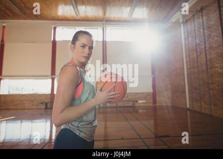 Determinata la High School girl in piedi con la pallacanestro in tribunale Foto Stock