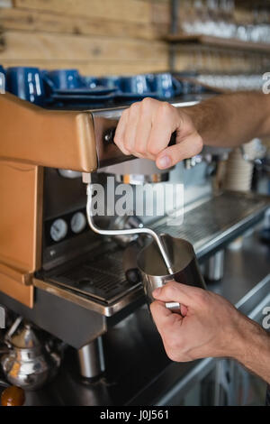 Close-up di cameriere mani versando il latte nel bricco da macchina da caffè cafÃƒÂ© Foto Stock
