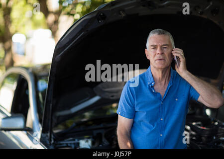 Tensionata senior uomo parlando al telefono dopo la ripartizione per auto Foto Stock