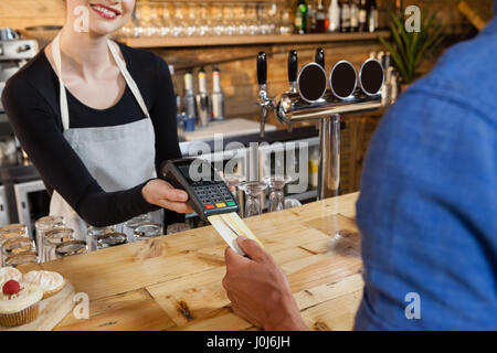 Uomo di effettuare il pagamento sul lettore di carte di credito macchina presso il cafe shop Foto Stock