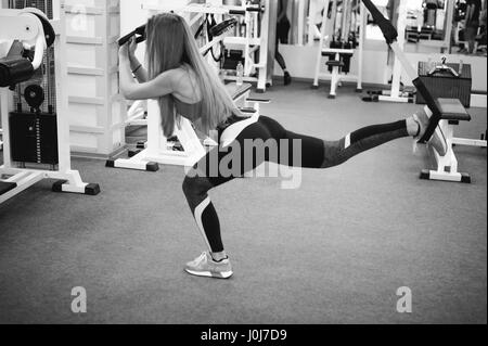 Bella donna atletica fare esercizio con sistema trx. Giovane donna che esercitano con sospensione trainer alla Palestra. Foto Stock
