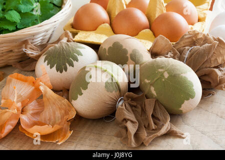 Uova di Pasqua decorate con foglie fresche, pronto per essere tinto con bucce di cipolla Foto Stock