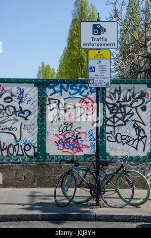 Una bicicletta puntellato contro un segno posto su Brick Lane nella zona est di Londra. Foto Stock