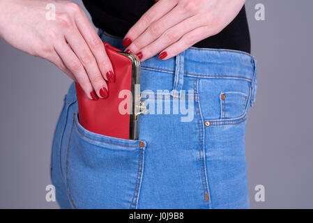 Donna che mantiene un portamonete rosso che ella è messa in suo pocket Foto Stock