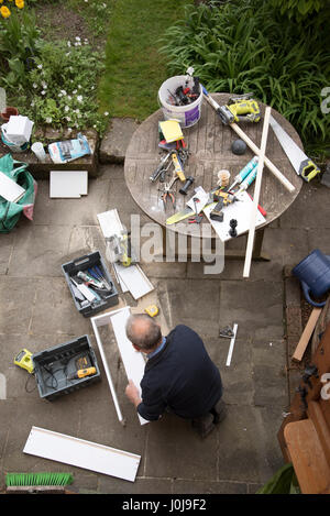 Una panoramica di un tuttofare impegnato in alcuni lavori di DIY su un giardino patio Foto Stock