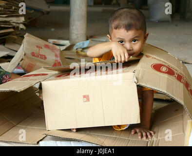 Il Viet Nam, Asian kid giocando con le scatole di cartone, i bambini vietnamiti con volto incantevole sedersi in negozio e giocare da solo mentre lavoro genitore, Vietnam Foto Stock