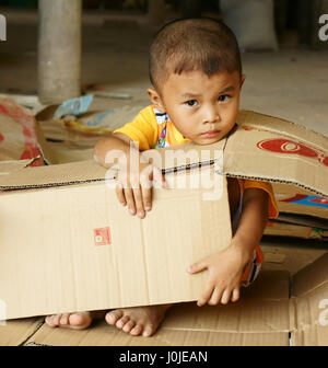 Il Viet Nam, Asian kid giocando con le scatole di cartone, i bambini vietnamiti con volto incantevole sedersi in negozio e giocare da solo mentre lavoro genitore, Vietnam Foto Stock