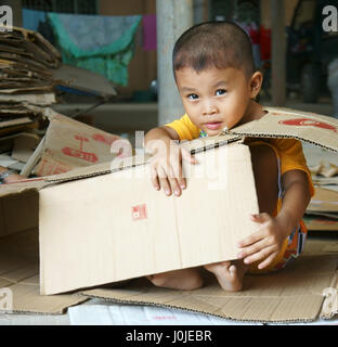 Il Viet Nam, Asian kid giocando con le scatole di cartone, i bambini vietnamiti con volto incantevole sedersi in negozio e giocare da solo mentre lavoro genitore, Vietnam Foto Stock