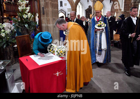 Queen Elizabeth II firma il libro degli ospiti durante il Royal Maundy service a Leicester Cattedrale dove ella distribuisce inoltre la tradizionale Maundy denaro a 91 uomini e 91 donne. Foto Stock