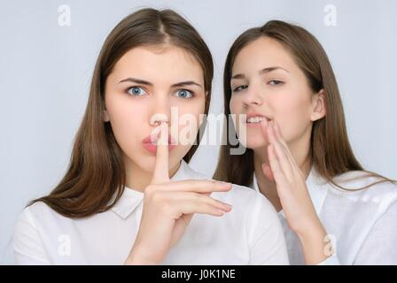 Giovane ragazza di pettegolezzo sussurrare al suo amico l orecchio Foto Stock