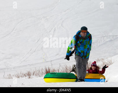 Padre e figlia con snow tube al giorno di sun. Montagne del Caucaso, Georgia. Stazione sciistica Gudauri. Foto Stock