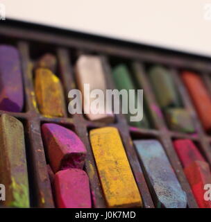 Un vicino la fotografia di una scatola di colorati utilizzati chalk pastelli, alcune rotte e in bit, colorata arte creativa fornisce l'immagine. Sfondo bianco. Foto Stock