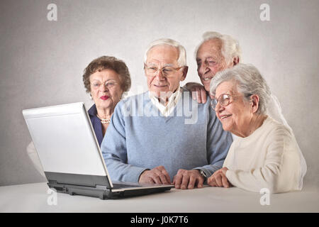 4 vecchie persone utilizzando laptop Foto Stock