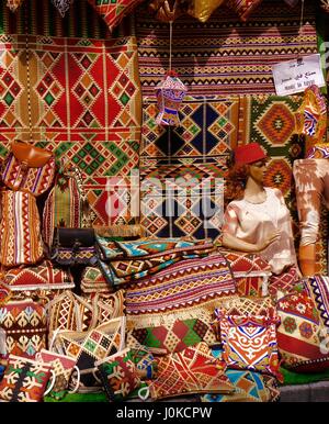 Display varia di tradizionali riccamente tappeti a motivi geometrici, tappeti, cuscini-copre, altri prodotti tessili souvenir in vendita in Khan al-Khalili Bazaar, il Cairo, Egitto Foto Stock