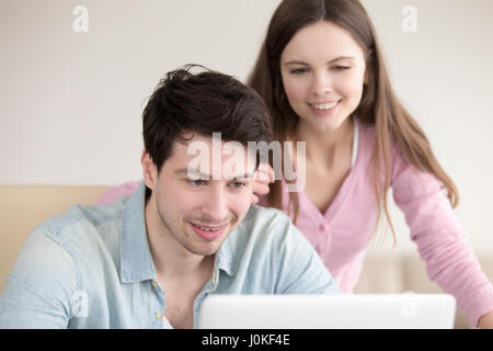 Giovane uomo sorridente e la donna utilizzando il computer portatile per interni Foto Stock