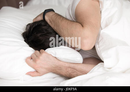 Uomo che si copre la testa con un cuscino nel letto, vista dall'alto.  Problema di insonnia Foto stock - Alamy