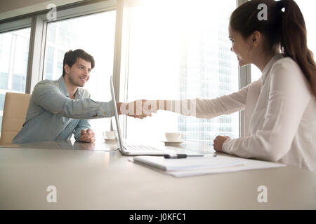 L uomo e la donna lo handshaking a office, business meeting, processo inte Foto Stock