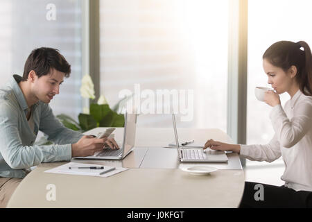 Maschi e femmine lavorano in ufficio utilizzando computer portatili aventi pausa caffè Foto Stock